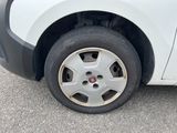 a small white car with a flat tire on the street