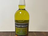 La bouteille de Chartreuse est posée sur une table en bois.
