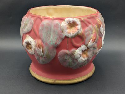 a pink vase with white flowers on it on a table