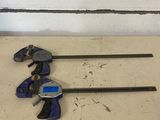 two clamps on the floor next to a pair of wrenches