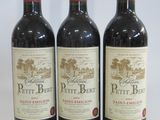 three bottles of red wine sitting on top of a white table