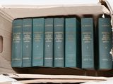 six books in a cardboard box on a white surface