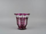 un vase en verre violet posé sur une table, sur fond gris