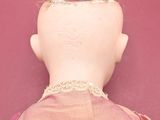 a doll that is laying down on a pink surface