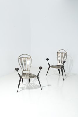 une paire de chaises en métal dans une pièce blanche au sol blanc