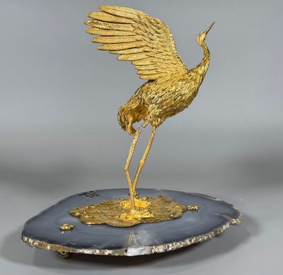 une image représentant une statue de grue en or posée sur une assiette noire et blanche