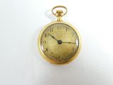 une montre de poche en or sur une surface blanche