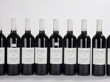 six bouteilles de vin rouge alignées sur une surface blanche