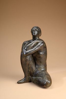 statue of a man sitting on the ground with his arms crossed