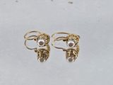 a pair of gold and pearl earrings on a white surface
