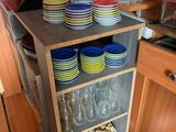 de nombreuses assiettes et verres empilés sur une étagère dans la cuisine