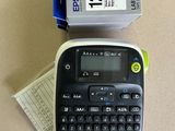 a black and white label printer next to a box of labels