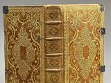 an old book with a golden cover sitting on top of a table