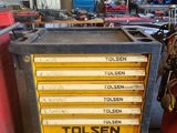 une boîte à outils jaune posée dans un garage, à côté d'autres outils