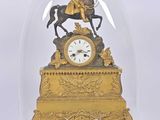 une horloge en or représentant un homme à cheval sous un dôme en verre