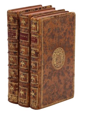 three old books are stacked on top of each other on a white surface