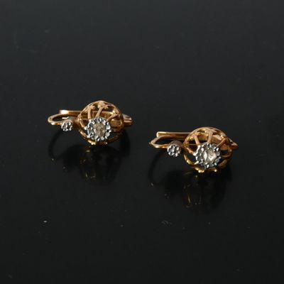 une paire de boucles d'oreilles en or et diamants sur une surface noire
