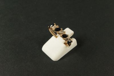 un gros plan d'une bague ornée de pierres noires sur un fond noir