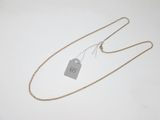 a gold chain with a tag attached to it on a white surface