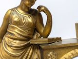 a statue of a woman sitting at a desk with a clock