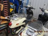 a scooter that is parked next to a pile of chairs