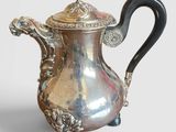 une cafetière ancienne en argent, dotée d'une poignée noire et d'une poignée noire