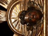 a gold statue of a man with a sun on it