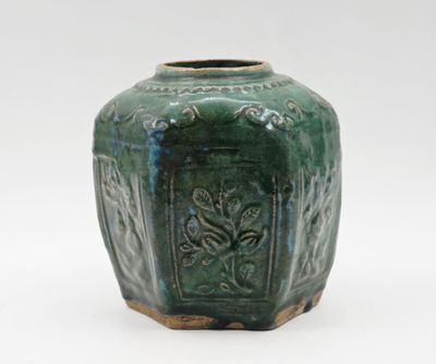 un vase vert posé sur une surface blanche, avec un fond blanc