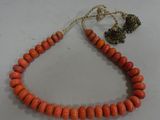 a close up of an orange beaded necklace on a white surface