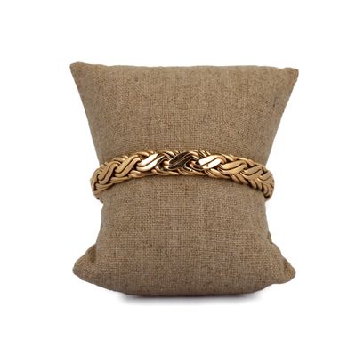 un gros plan sur un oreiller sur lequel repose un bracelet en or