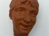 a clay sculpture of a woman ' s face on a white surface
