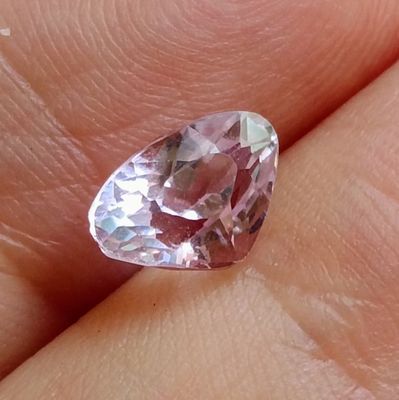 someone is holding a pink diamond in their hand on a finger