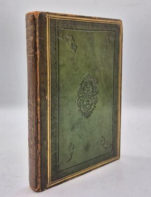 un vieux livre à la couverture verte posé sur une surface blanche