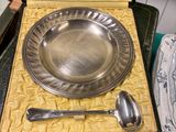 a silver plate with a spoon and a spoon rest in a case