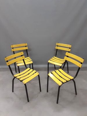 une paire de chaises en métal jaune adossées à un mur gris dans une pièce