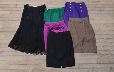 several skirts are lined up on a wooden floor next to a hanger