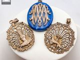 trois pendentifs dorés et bleus posés sur une assiette blanche posée sur une table