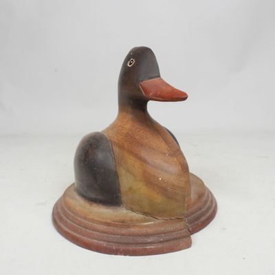 statue d'un canard posé sur un socle, sur une surface blanche
