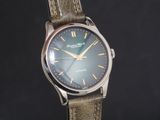 une montre en argent avec un cadran vert et un bracelet marron