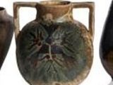 trois vases munis d'anses de chaque côté, posés sur une surface blanche