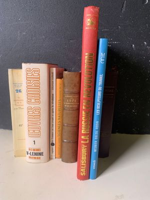 Plusieurs livres sont alignés sur une étagère devant un mur noir
