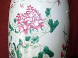 a vase with a pink flower and green leaves on it