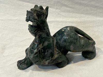 a statue of a dog laying down on a white surface