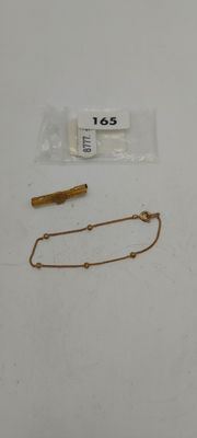 une chaîne en or et un bracelet en or posés sur une table blanche