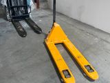 un chariot élévateur jaune garé à côté d'une pile de palettes