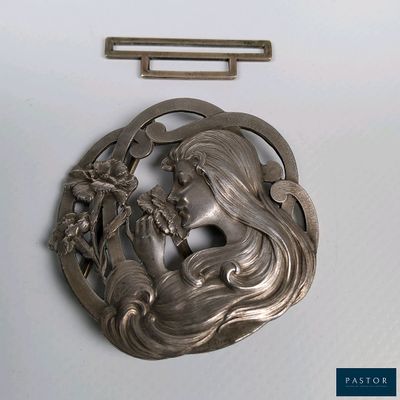 une broche en argent représentant une femme et des fleurs