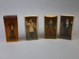 three miniature figurines of people in boxes on a white surface