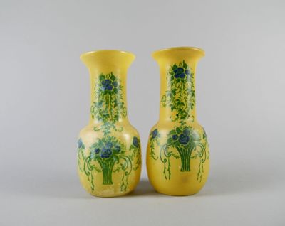 une paire de vases jaunes ornés de fleurs bleues sur fond blanc
