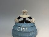 a figurine of a woman in a blue dress sitting on top of a cake