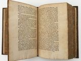 an old book opened to reveal a page of text on a white surface